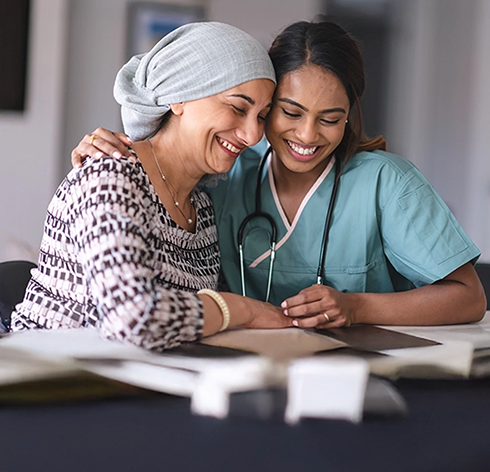Une infirmière réconfortant une femme souriante portant un foulard, symbolisant les soins et l'orientation du TNBC au Canada