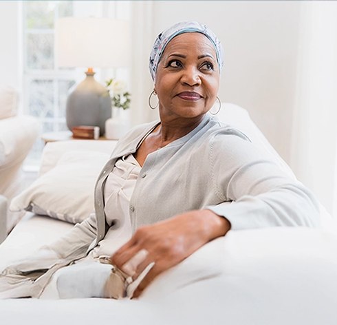 Une femme portant un foulard assise sur un canapé et semblant pleine d'espoir, symbolisant la résilience du TNBC au Canada